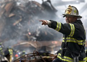 Notre Action A firefighter in action at a disaster scene, directing rescue operations amidst smoke and debris.